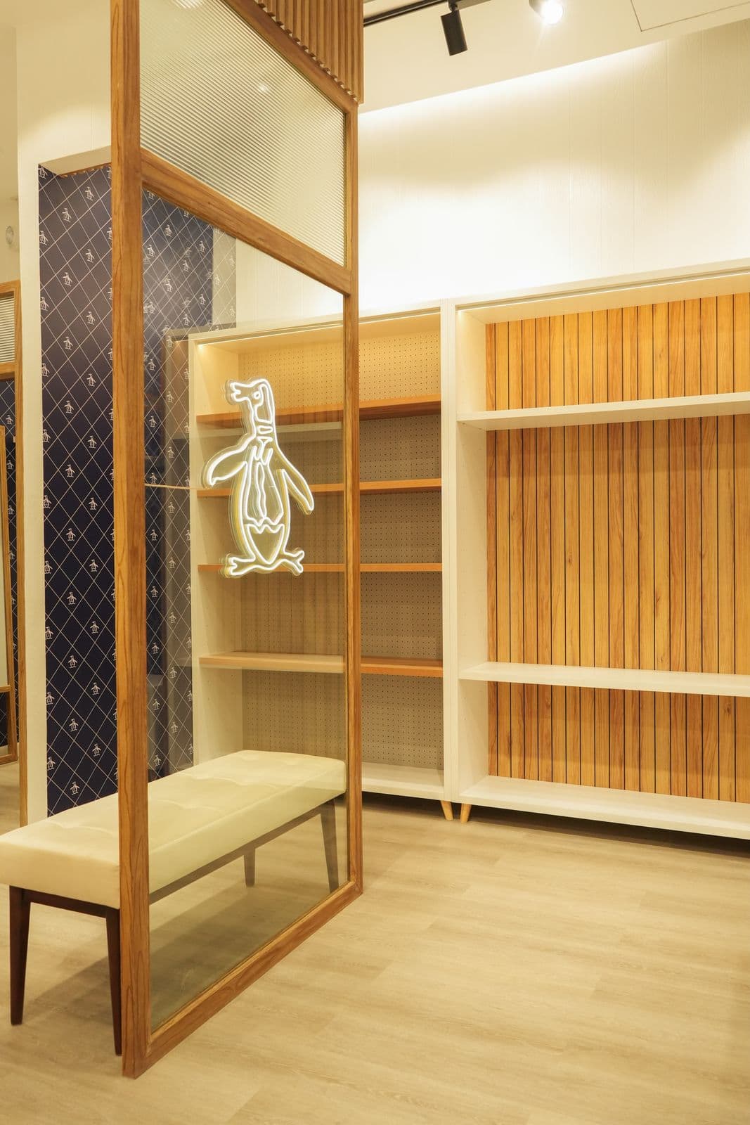 Neon penguin logo glass installation on navy diamond-pattern wallpaper