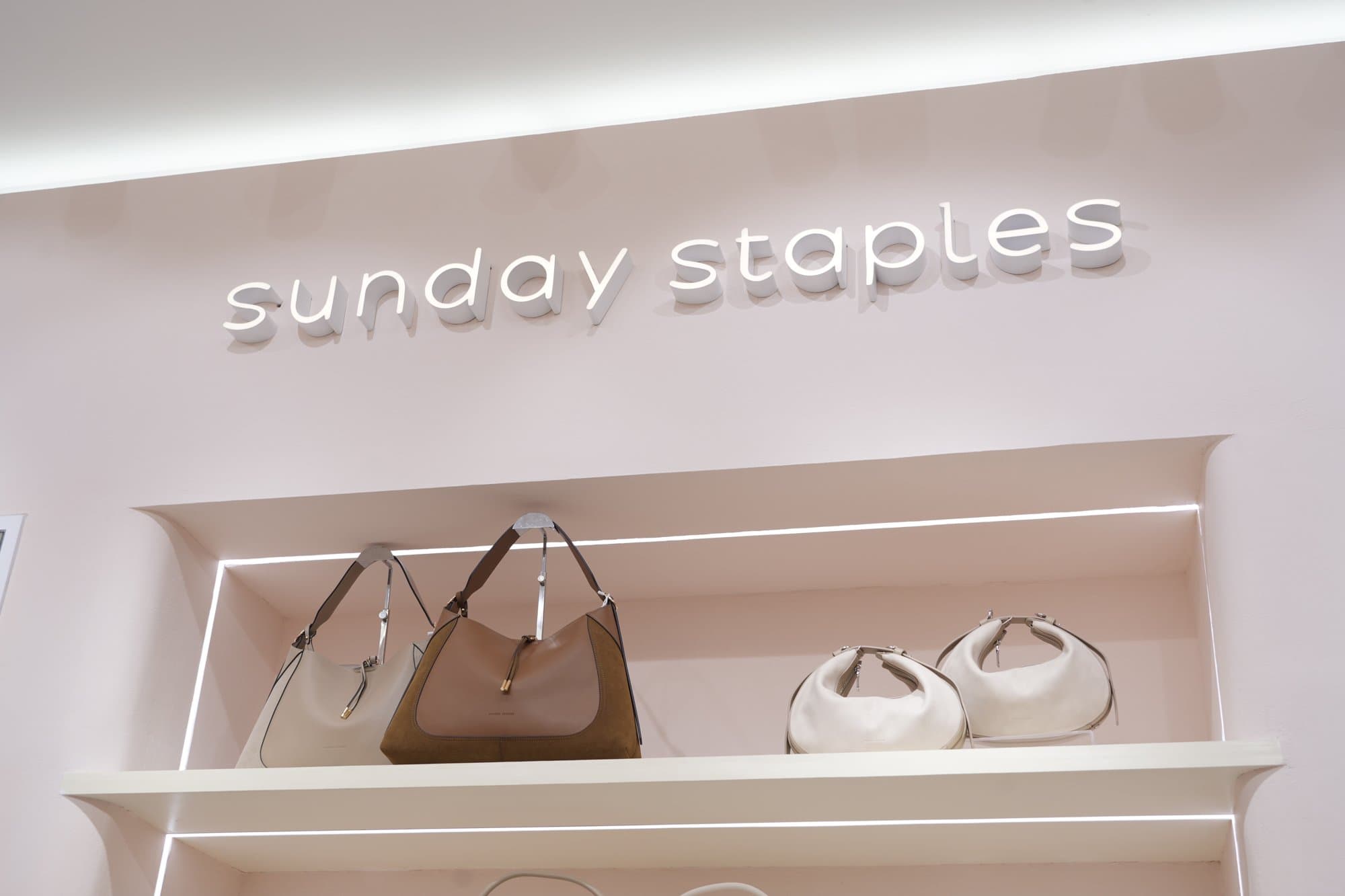 Sunday Staples interior with island display tables, LED wall shelves, and pink millwork