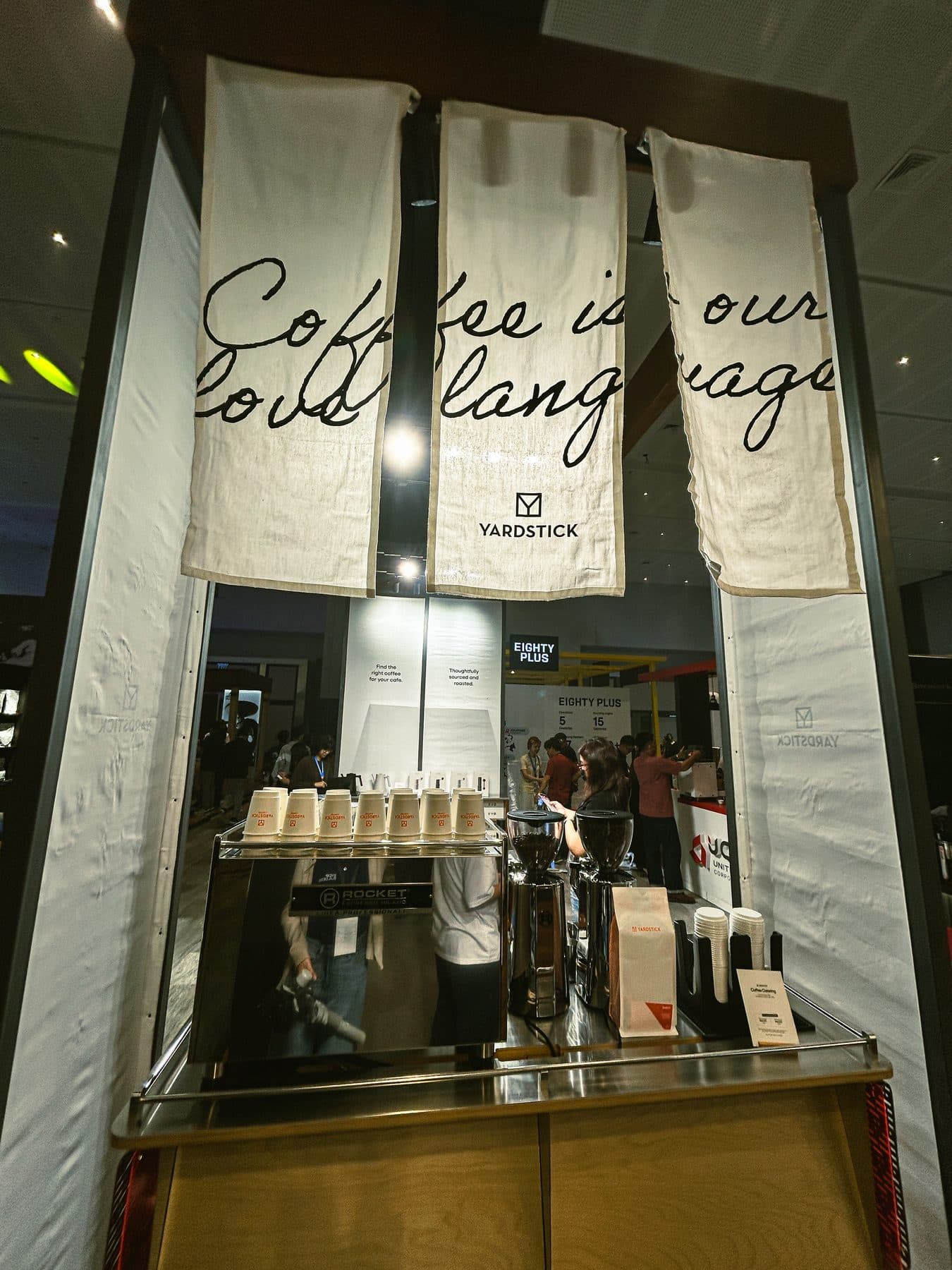 Yardstick booth opening showing millwork, service counter, and branded ceiling banners